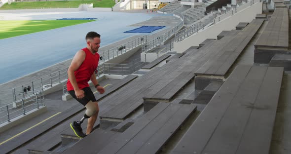 Caucasian disabled male athlete with prosthetic leg training, running up stairs
