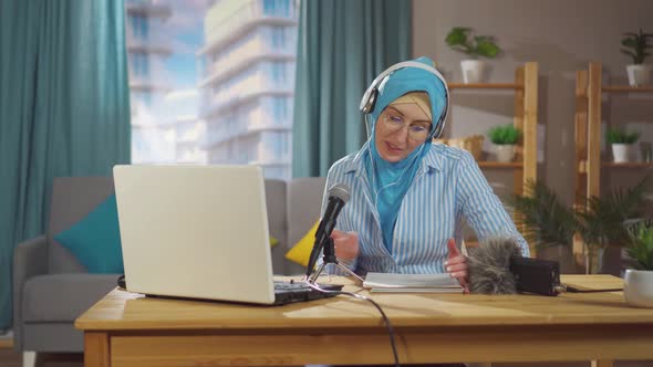 Young Muslim Woman Records a Podcast While Sitting in Front of a Microphone in Her Living Room