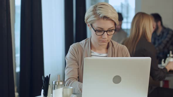 Busy Young Woman Working on Laptop in Cafe