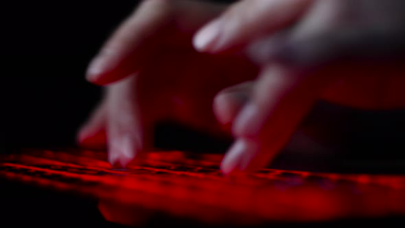 Hacker Girl's Hand Typing on Keyboard with Red Backlight