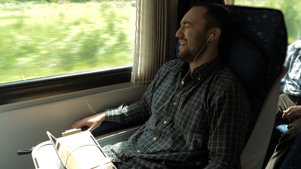 Young man listening to the music on the train and sings