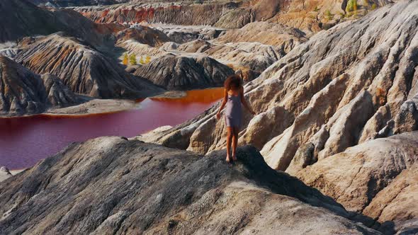 Aerial View of a Girl Who Climbs the Red Mountains in a Dress