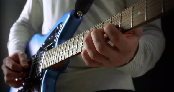 Creative Musician in a Gray Jumper on a Black Background Plays Electric Guitar