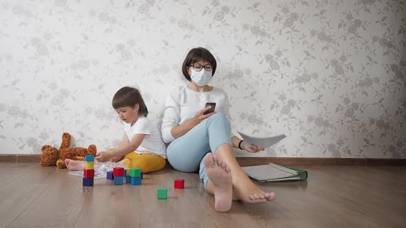Mom and Son Sit at Home Quarantine Because of Coronavirus COVID19. Mother Works Remotely with