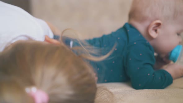 Little Girl and Funny Baby Trying to Drink Water on Bed