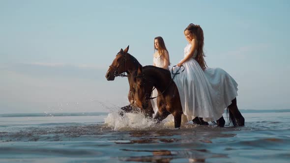 Two Beautiful Girls in White Long Dresses on Horseback