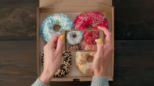 Woman's Hands Take Pictures with Smartphone of Delicious Donuts in Box