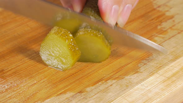 Pickled cucumber cutting on small pieces with knife on wooden board 4K 2160p UHD footage - Gherkin p