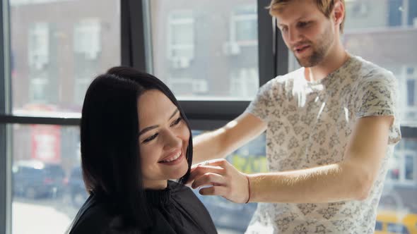 A Woman in a Hairdressing Salon Waiting To See the Results Looking in a Mirror, Smiling and Talking
