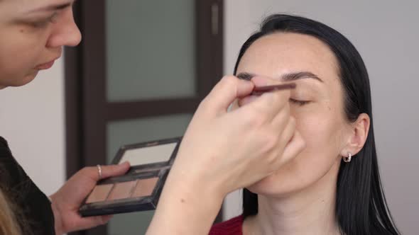 Closeup of a Young Woman Applying Shadows on Her Eyes