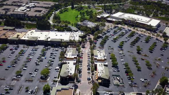 Aerial panning shot of a shopping mall strip mall to roads and then mountains in the background pan2