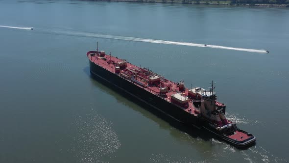 A drone view of a large red barge on the Hudson River in NY. Taken on a sunny day with three small w