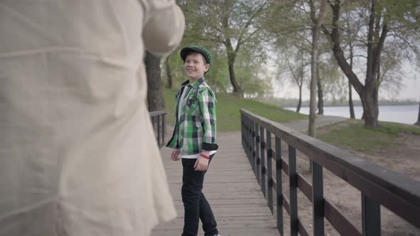 Grandfather and Grandson Walking in the Park on a Bridge