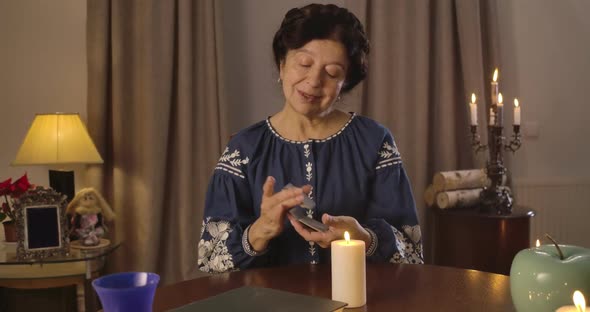 Camera Moving From Left To Right Around Mature Caucasian Woman Shuffling Cards at the Table