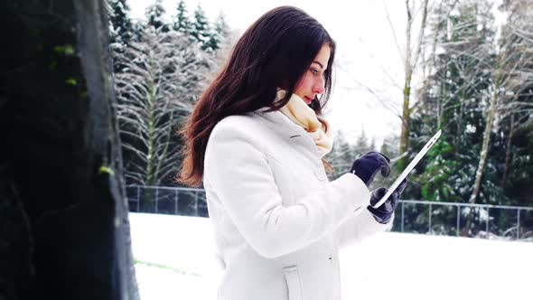 Beautiful woman in warm clothing using digital tablet
