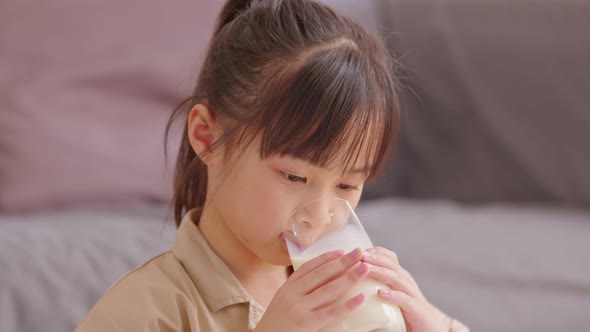 Happy Asian Kid drinking fresh milk for good health at home