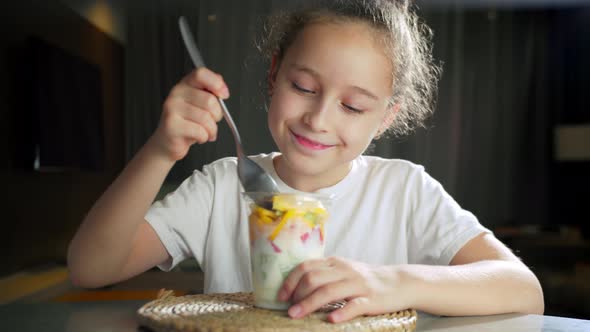 Child Eats Milk Yogurt with Tropical Fruits