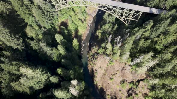 High Steel Bridge over an expansive chasm with a river flowing below, looking down aerial