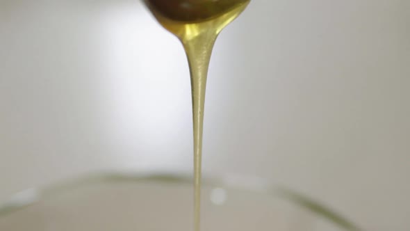 Close up of honey dripping off spoon in slow motion