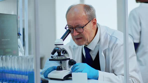 Laboratory Scientist Conducting Experiment Looking at Microscope in Busy Lab