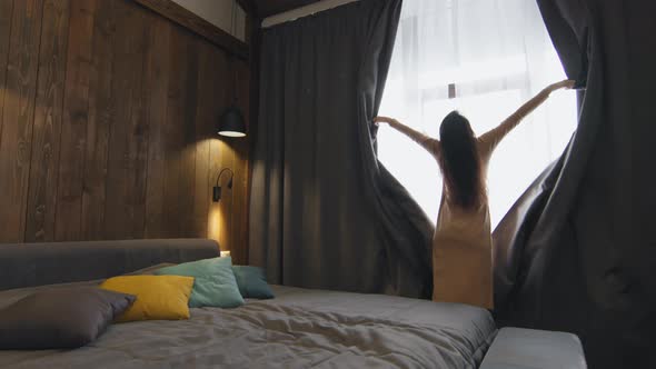 Woman Opening Curtains In Hotel Room