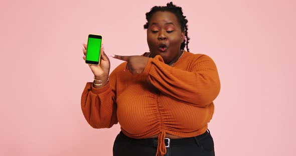 Black Model Holds Phone and Points Out on Gadget Screen