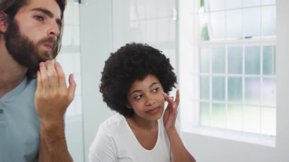 Mixed race couple looking in the mirror in bathroom at home
