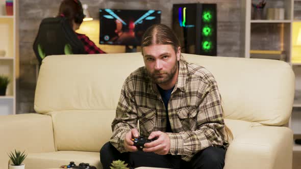 Focused Bearded Man Sitting on Couch Playing Video Games