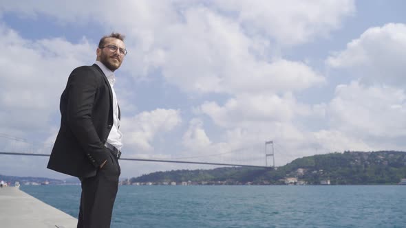 Thoughtful businessman against the sea by the strait in the city.