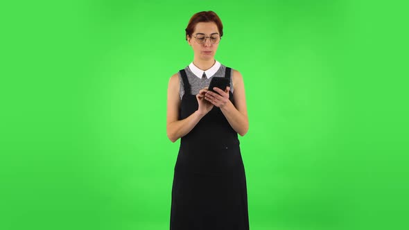 Funny Girl in Round Glasses Is Texting on Her Phone. Green Screen