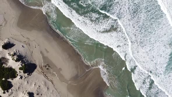 waves roll on the beach of rena majore in sardinia, bird's eye view with the drone