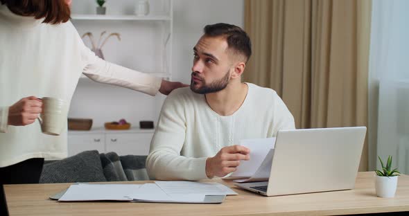 Caucasian Business Man Freelancer Husband Works at Home Sits at Table in Front of Laptop Looks at