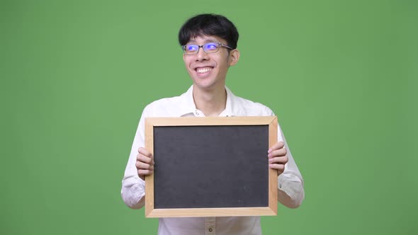 Young Asian Businessman Holding Blackboard While Thinking