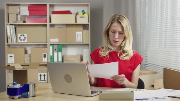 Warehouse Worker is Working in an Office Room Against Background of Boxes