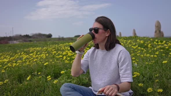 The Girl Drinks Tea Sitting on the Green Grass