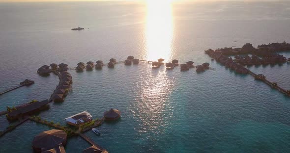 Aerial flight towards stunning sunset over ocean and huts in Mabul, Malaysia