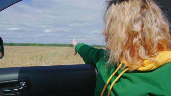 Blonde Passenger in Car Enjoys Countryside View