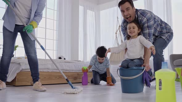 Joyful Dad Riding Daughter on Bucket During Clean