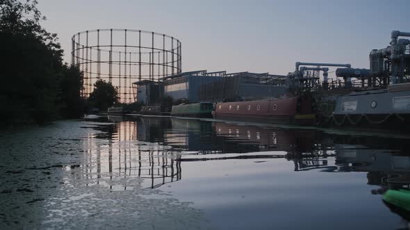 Man going on urban kayak adventure during sunset creating ripples in water, green inflatable canoe