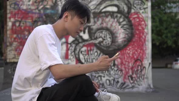 Young Asian Man with Smartphone on the City Street