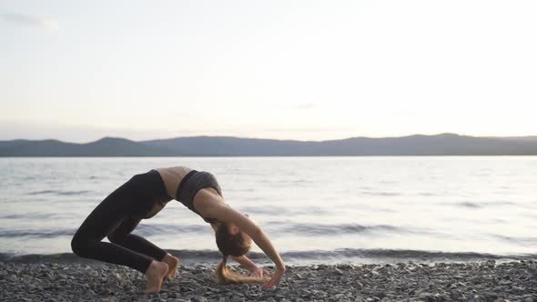 Young Slim Happy Woman with Long Hair in Sportswear Doing Yoga and Exercises on the Beach at Sunrise