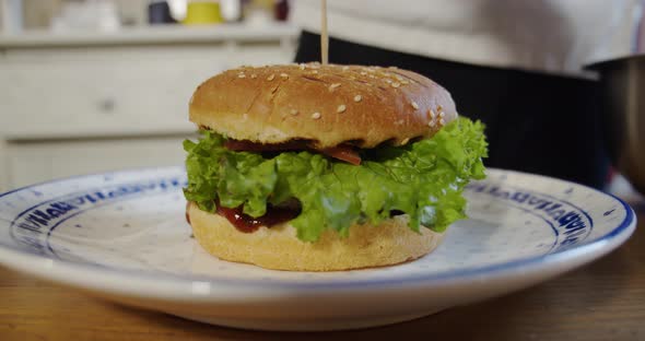 Chef Puts French Fries on a Plate with a Large Burger. Slow Motion. Close Up