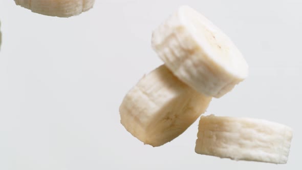 Camera follows tossing sliced banana in milk. Overhead shot. Slow Motion.