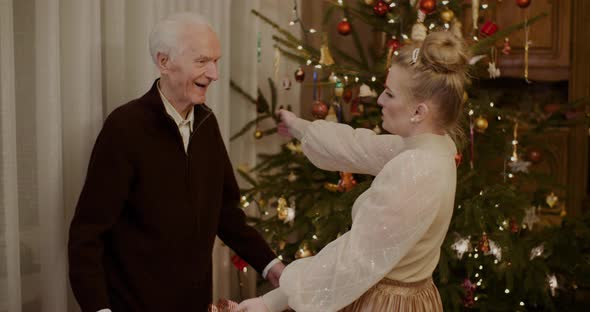 Woman Giving Christmas Present To Grandfather At Home