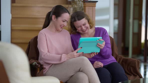 Joyful Carefree Caucasian Adult Mother and Young Daughter Laughing Watching Funny Videos Online on