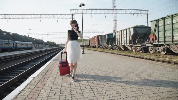 Happy Lady Goes with Suitcase and Poses with Dress on Railway Platform
