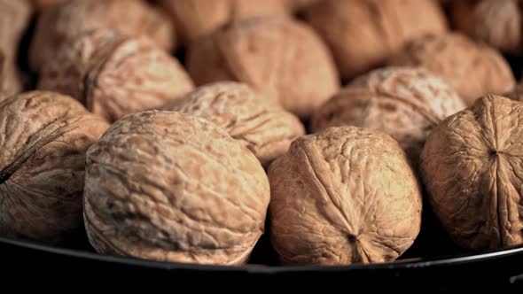 Lot of Walnuts in the Shell are Spinning on a Black Background