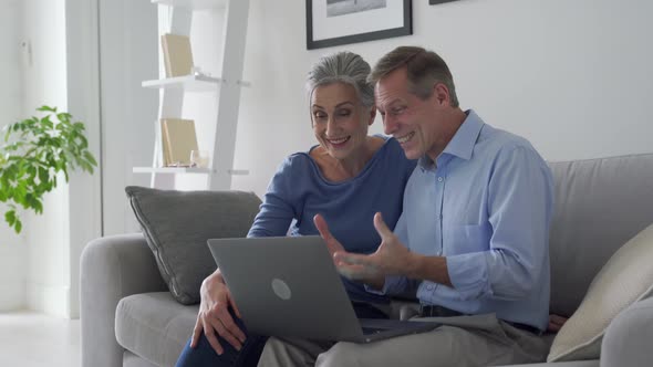 Happy Senior Couple Talking Looking at Laptop Making Online Video Call