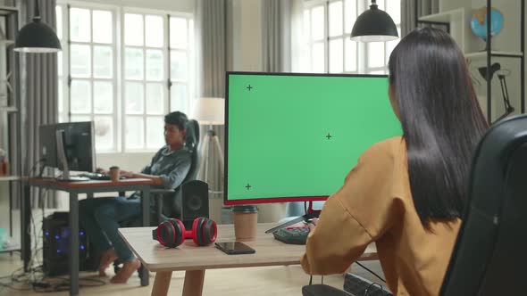 Back View Of Asian Female Works With Mock Up Green Screen Computer Display In Office