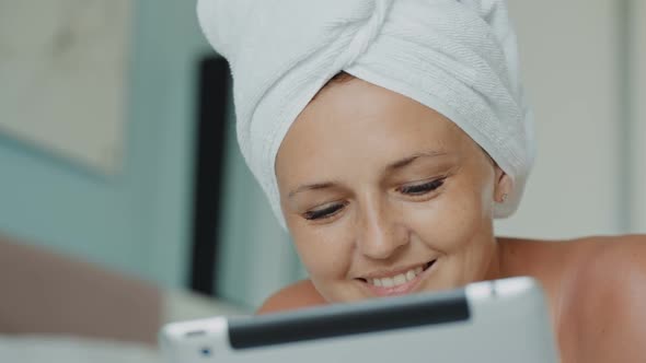 Woman in Bath Towel Browsing Social Media Posts While Lying on Couch